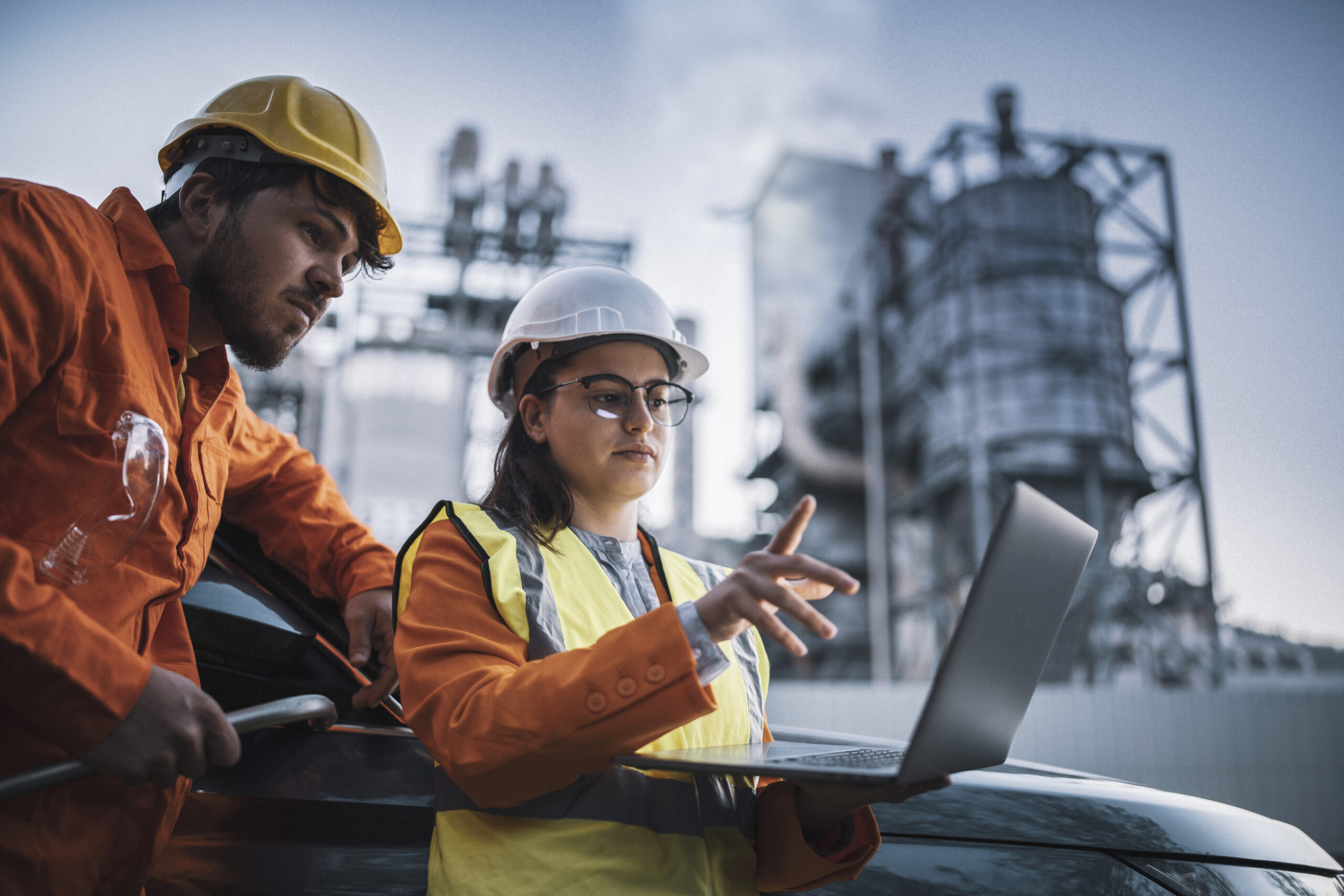 Two engineers man and woman using laptop to work at power plant on night shift.